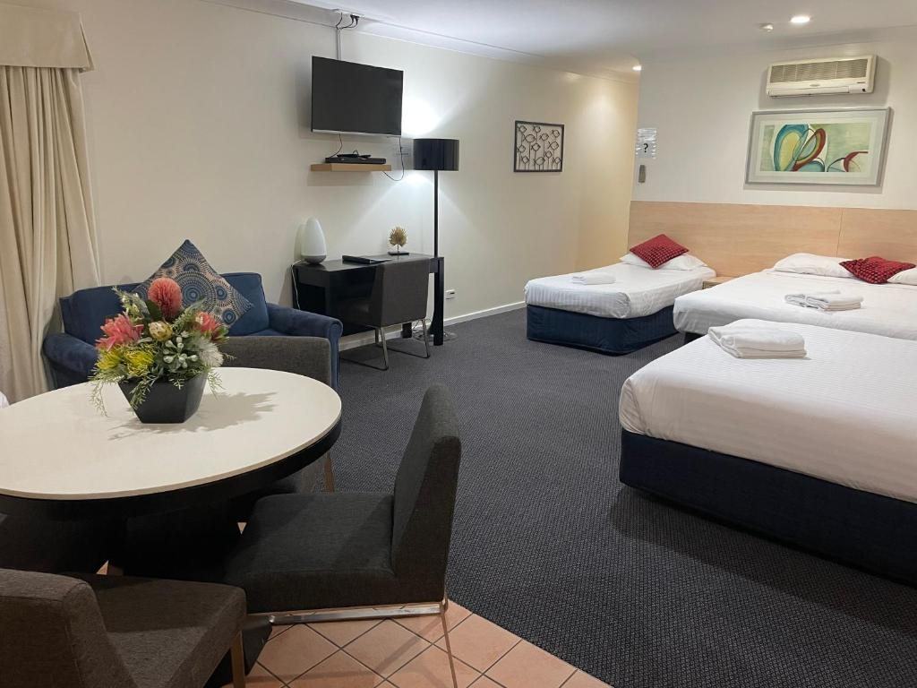 Spacious family room with a lounge, dining table and two beds at Lakeview Motor Inn